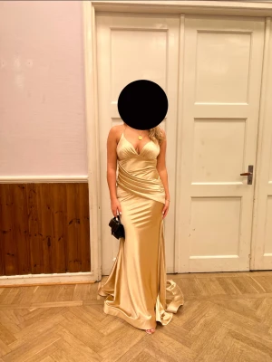 Balklänning  - Jätte fin guldig balklänning köpt i oktober 2022 inför en förlovningsfest. Använt den 1 gång och är köpt från Pink & Purple Malmö. Fint skick. Passar perfekt inför balen nu! Banden går att justera. Jag är normalt en S men den skulle nog passa Xs-M då.