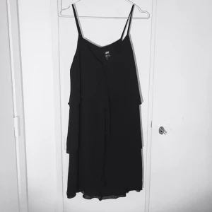  - Svart klänning med volang fr H&M. Använd ett fåtal gånger. Fin som den är till fest, eller med t-shirt under till vardags. 