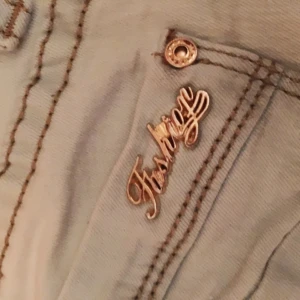  - Ljusblåa byxor från Miss RJ med gulddetaljer. Har en liten svart fläck på ena backfickan