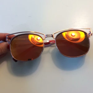  - Rosa spegelglas solglasögon, bågarna är metallic rosa och glasen är orange-rosa spegelglas