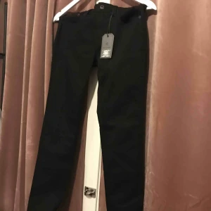  - Helt oanvända svarta jeans i stretchigt material, prislapp kvar. Snyggt slitna vid byxbenen