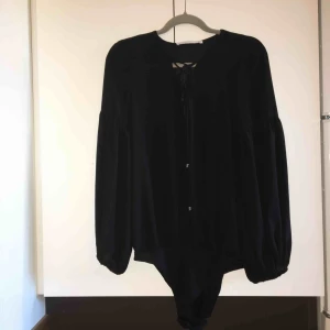  - Svart body från Zara. Knytning fram vid bröstet och vidare ärmar. Slitage vid knäppe (se bild 3). Kan mötas upp alt. skicka.