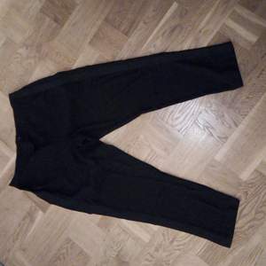 Svarta byxor från Ellos med glansigt svarta revärer i sidorna. Ankellängd. Använd ett fåtal gånger. Vet ej material.