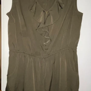 Byxdress militärgrön stl 44 Primark - Snygg militärgrön byxdress från Primark i stl 44. Knappt använd, har dock en fläck som syns mer på bild med blixt än med blotta ögat. Inget som stör eller syns överhuvudtaget. Kommer från djur- och rökfritt hem. Frakt tillkommer!