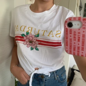 Vit t-shirt med tryck med knyte - Vit t-shirt med tryck ”SATURDAY” med knyte från H&M. Använd endast en gång! Bra skick! Köparen står för frakten (: