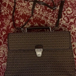 Tony Perotti  - Köpte denna på tradera, passade inte alls dessvärre.   portfölj textil med detaljer av läder/läderliknande Bredd ca 40 cm Höjd ca 28 cm  Djup ca 11 cm Inuti portföljen tre fack varav en med dragkedja Mindre fack för penna mm Portfölj ligger i medhavd textilbag  Skick som nytt