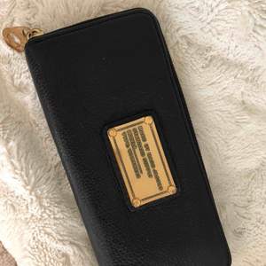 Marc Jacobs plånbok i svart med gulddetaljer. Naturliga slitningar på gulddetaljerna på märket. Använd fåtal gånger.   Inköpt för 2199kr på Raglady i Göteborg   FRI FRAKT!