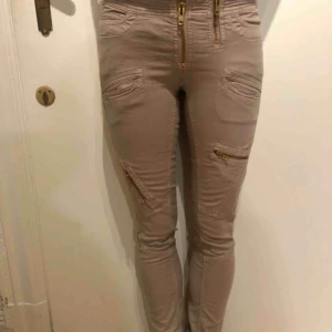  - Coola byxor med guldkedjor som detaljer från By Marlene Birger. Storlek 26/32. Personen är 170 cm och har storlek small.