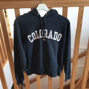  - Hoodie från H&M i mörkblå. Små bristningar i texten. 