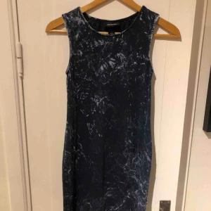  - Mörkblå klänning med vitt spräckligt mönster från Monki i Small. Kort och tajt modell.