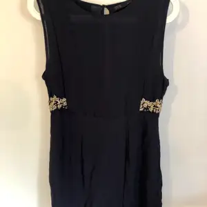 Jättefin klänning från Zara med chiffong och brodyrdetaljer i guld i midjan. Färgen är väldigt mörk blå men nästan svart. 