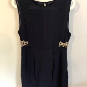 Finklänning från Zara - Jättefin klänning från Zara med chiffong och brodyrdetaljer i guld i midjan. Färgen är väldigt mörk blå men nästan svart. 