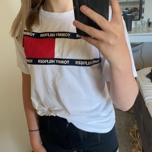 Tommy hilfiger t-shirt  - Vit T-shirt från Tommy hilfiger. Den har två små fläckar med den stan inte när man stoppar in tröjan. Den är sådär stor i storlek. Högst bud får den (pris+frakt)