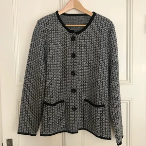 Mönstrad stickad kofta  - Mönstrad och mjuk stickad kofta med fickor och svarta detaljer. Har små axelvaddar som ger snygg figur, använd endast 1 gång. Frakt tillkommer. 