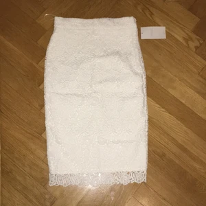  - Elegant vit spets kjol (midi). Slits baktill, stängning med dragkedja på sidan. Perfekt för dop. Oanvänd med prislapp kvar!