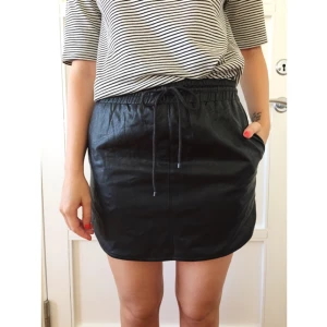 - Supersnygg och bekväm kjol i skinnimitation och sportig modell. Aldrig använd. Yttertyg: polyuretan. Foder: polyester.  