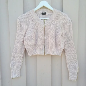  - Cremefärgad kofta i kortare modell. med liten puffärm och snyggt stickmönster. 100% bomull. Fräscht  begagnat skick.