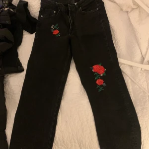 Jeans med rosor från H&M i storlek 42 - Jeans med rak modell med rosor på, passar 38-42 beroende på hur man vill att de ska sitta. Stretchiga och i jättebra skick! 
