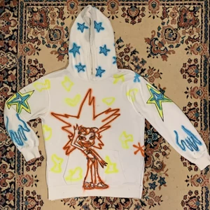 Vit handgjord spraymålad custom retro hoodie Ruby Trollz & graffiti stjärnor  - Vit custom made handgjord spraymålad graphic hoodie med all over tryck av Ruby från det ikoniska programmet Trollz samt graffiti stjärnor på luvan, ärmarna och ryggen + händer vid muddarna av ärmarna och abstrakta former på framsidan 🎨 Som snyggast till ett par mörka jeans eller byxor för att få hoodien att verkligen sticka ut och ett par skor med färgglada detaljer för att knyta ihop hela outfiten (tips: eftersom hoodien ser ut som någonting direkt från det tidiga 2000-talet så kan ni maxa outfiten med y2k accessoarer som ett par ramlösa solglasögon och ett trucker hat!)