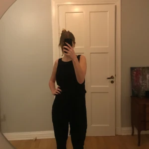 Svart jumpsuit med virkade detaljer - Så snygg och bekväm svart jumpsuit. Virkade detaljer både bak och fram. Fickor och snören man kan dra åt i midjan. Nyskick! Kan frakta och mötas upp!