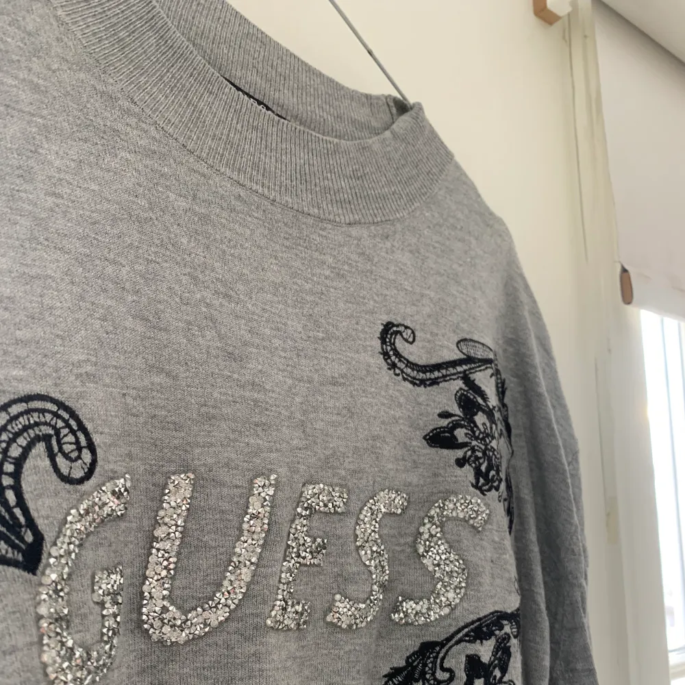 En grå tröja från Guess med ett broderat tryck, text av reinstones            Köparen står för frakten . Tröjor & Koftor.