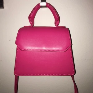 Rosa axelremsväska, Ginatricot, 60kr - Jätte fin, liten axelremsväska från ginatricot, köpte både den och en likadan orange i somras för 280kr styck. Har dock inte använt dom utan har bara haft dom hemma som prydnad. Säljer en för 70kr och båda två för 110kr. Man kan bära den både för hand om på axeln så den har både handtag och en lång axelrem. Deras riktiga namn är ”nea bag”💓 priset går att diskuteras☺️