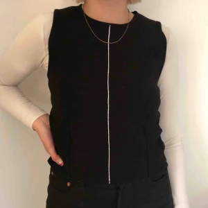  - Svart slipover med ett vitt sträck i mitten! Från Zara i strl M. Funkar perfekt att ha över en vit longsleeve. Oanvänd så lappen är kvar! Köparen står för ev frakt!🌼