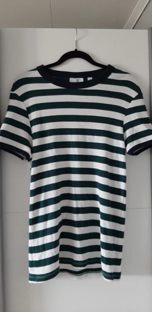 Randig T-shirt - En ribbad längre t-shrit från Collusion. Vit/Mörkgrön. Krage och ärmmudd är mörkblåa. Unisex. Sitter åtsittande. Frakt ingår.