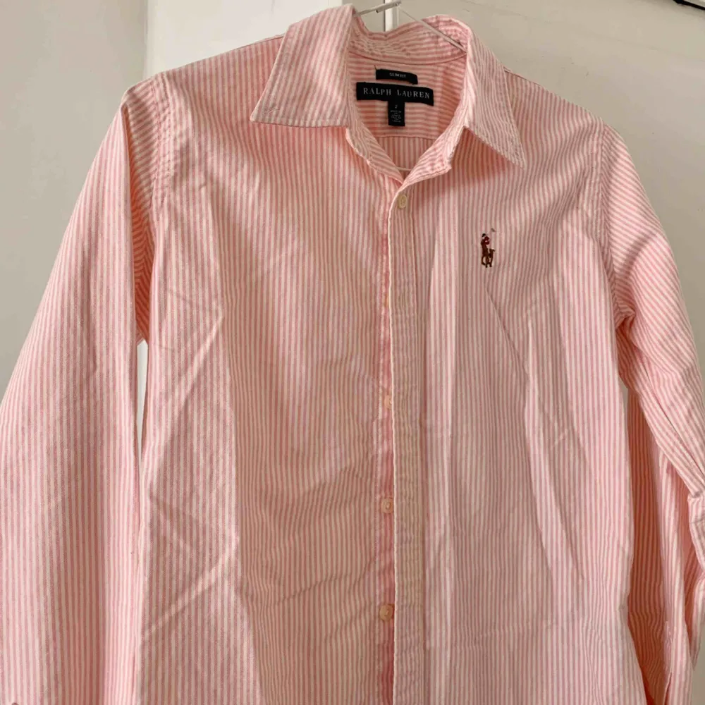 Vit- och rosarandig skjorta från Ralph Lauren. Figursydd Använd endast ett fåtal gånger, i mycket fint skick! Storlek US 2/XS. Möts upp i Stockholm eller så står köparen för frakt. 🌸. Skjortor.