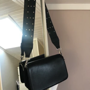axelväska från nelly - svart axelväska från Nelly i bra skick. har även ett annat ormimiterat band som man kan få med helt gratis. 