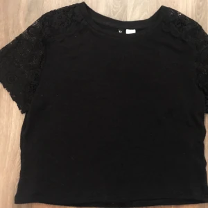 Svart T-shirt med spets - Jättesöt svart T-shirt med spets över axlarna. Endast använd någon gång så i mycket fint skick utan tecken på användning. Väldigt stetchig men också lite genomskinlig. Priset inkluderar frakt. Skriv privat för eventuella frågor eller för mer bilder.
