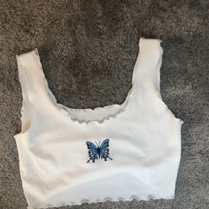 Söt fjärils topp shein - Säljer min oanvända ribbade topp från shein. Supersöt med en broderad fjäril på. Frakt tillkommer på 45kr! 