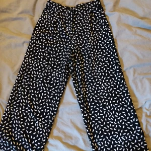 Kostymbyxa Monki, storlek 32 - Kostymbyxor med mönster, vida ben. Plagget är ca 85cm långt, har kortare ben och två fickor fram. Använda ett fåtal gånger. Säljer pga för liten. Köpare står för frakt.