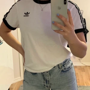 Adidas t-shirt. Strl:36. Färg:vit, svart - Adidas t-shirt med tre streck på ärmarna och konstrast i alla ändar. I bra skick. Nypris 299kr, säljs för 100kr. Strl 36 ifrån Adidas🖤