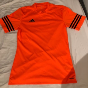 Orange adidas träningströja - Orange adidaströja med svarta detaljer i strl S säljes. I väldigt bra skick och med en snygg orangefärg!! Köparen står för frakten, fraktkostnaden är ungefärlig. Priset för tröjan är 80kr eller högsta bud. 