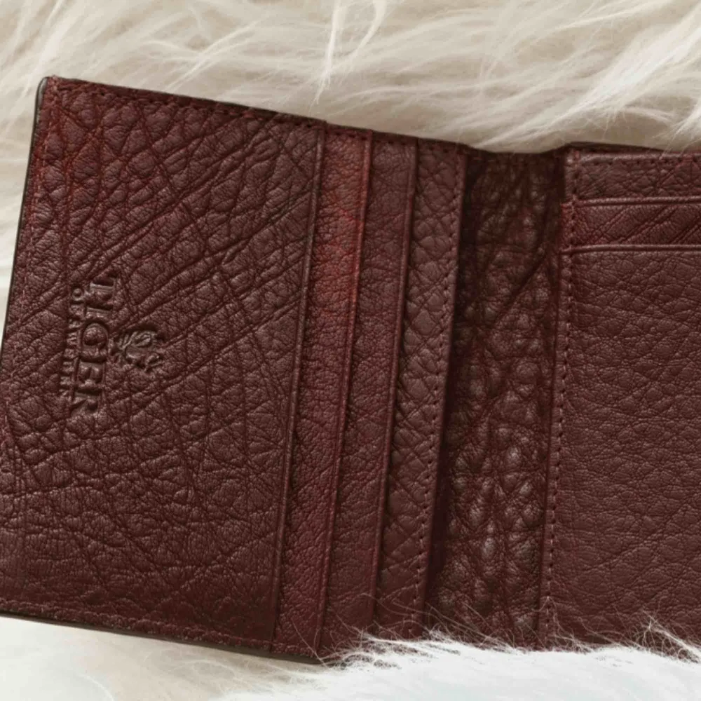 En sjukt snygg plånbok från Tiger Of Sweden i en rödbrun färg med textur. Många fack för kort, myntfack och även sedelfack. Nypris 800kr. Priset går alltid att diskutera!. Accessoarer.