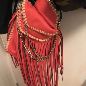  - En röd fransväska, medelstor. 