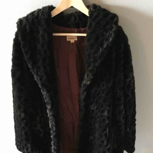  - Fuskpäls i diskret ”leopard” mönster. Svart/brun till färgen. Knäpps framtill med ”hakor”. Köpt på beyond retro. Använd men mycket gott skick!