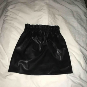  - Riktig snygg skinnkjol i Strl. Den har en ficka på vardera sida (väldigt praktiskt) och ett resårband i midjan som skapar illusionen om att man är mer kurvig. Helt oanvänd. Om du önskar fler bilder är det bara att skriva så kan jag ordna det :)