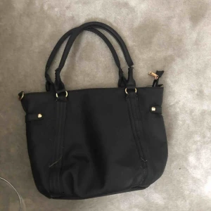  - Enkel, snygg, rymlig och svart väska med gulddetaljer. Lite sönder vid handtaget🥰