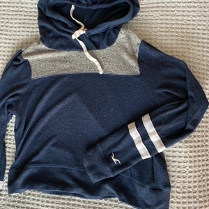 Hollister mjukiströja - Lite croppad huvtröja i JÄTTEmjukt material från Hollister. Perfekt att bara mysa i eller ha på gymmet! (Ser ut som en fläck på tröjan men är bara ludd!) Köparen står för frakten. Priset kan diskuteras!