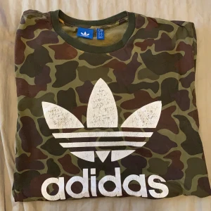 Adidas T-shirt  - Adidas T-shirt i camouflagemönster. Storlek M. 