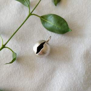 Hängsmycke i silver till halsband. Det är en liten svart pärla inuti som låter lite när det rör sig. Kulan är ca 1.5 cm i diameter. Frakt: 9 kr.