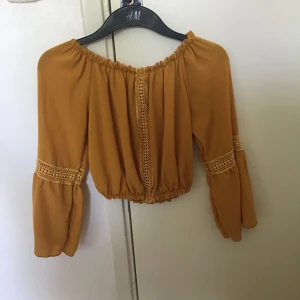  - En smutsgul färgad crop topp med utsvängde ärmar, använd en gång. Vet ej vart jag köpt den ifrån men den har bara hängt i garderoben och jag får ingen användning till den