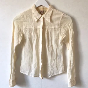  - Vit/beige skjorta, blus, i linne-aktigt material och struktur/crepe i tyget. Supersöt! Gott skick. Material: 100% bomull Storlek: 34, XS, S, 36  Kan mötas i Stockholm eller skicka mot fraktkostnad! ✨🌸✨