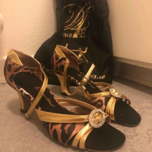  - Dansskor dam i storlek 8 (USA), motsvarar stl 38/39. Skorna är oanvända. Mockasula. Skopåse ingår.  Färg: Leopard Satin & Gold  Klackhöjd: 2,25 cm