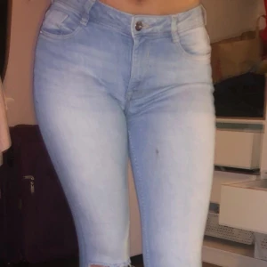 Ljusblå jeans - Ljusblåa jeans med hål i knäna och fransade nertill, fråm H&M DIVIDED,, säljer pga att dom sitter lite för tajt och inte kommit till användning, finns en liten fläck på låret men inget man tänker på!