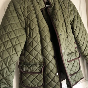 Quiltad damjacka från VILA - Olivgrön, quiltad damjacka med detaljer i brun fejkmocka. Storlek XS, men passar även S. Använd ett fåtal gånger. 
