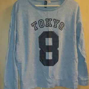 Grå långärmad tröja Strl. M - Långärmad grå tröja från H&M Strl. M med texten "tokyo" och en 8:a. Välanvänd men inga fläckar eller så. Priset kan diskuteras. Skickas mot fraktkostnad.