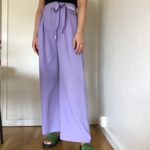 Samsøe Samsøe lila byxor - Väldigt fina lila byxor med snörning i midjan. Högmidjade. Bekväma. Jag är 167 och de går precis till hälen på mig. Väldigt bra skick.